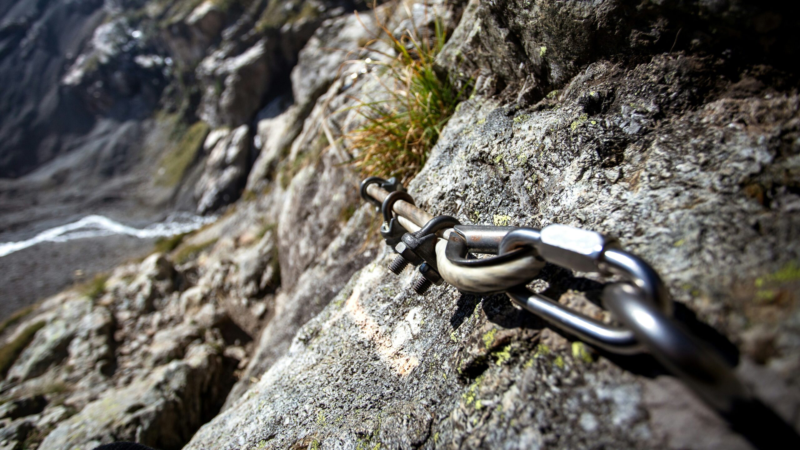 A climber using a traditional belay device while checking their knot.