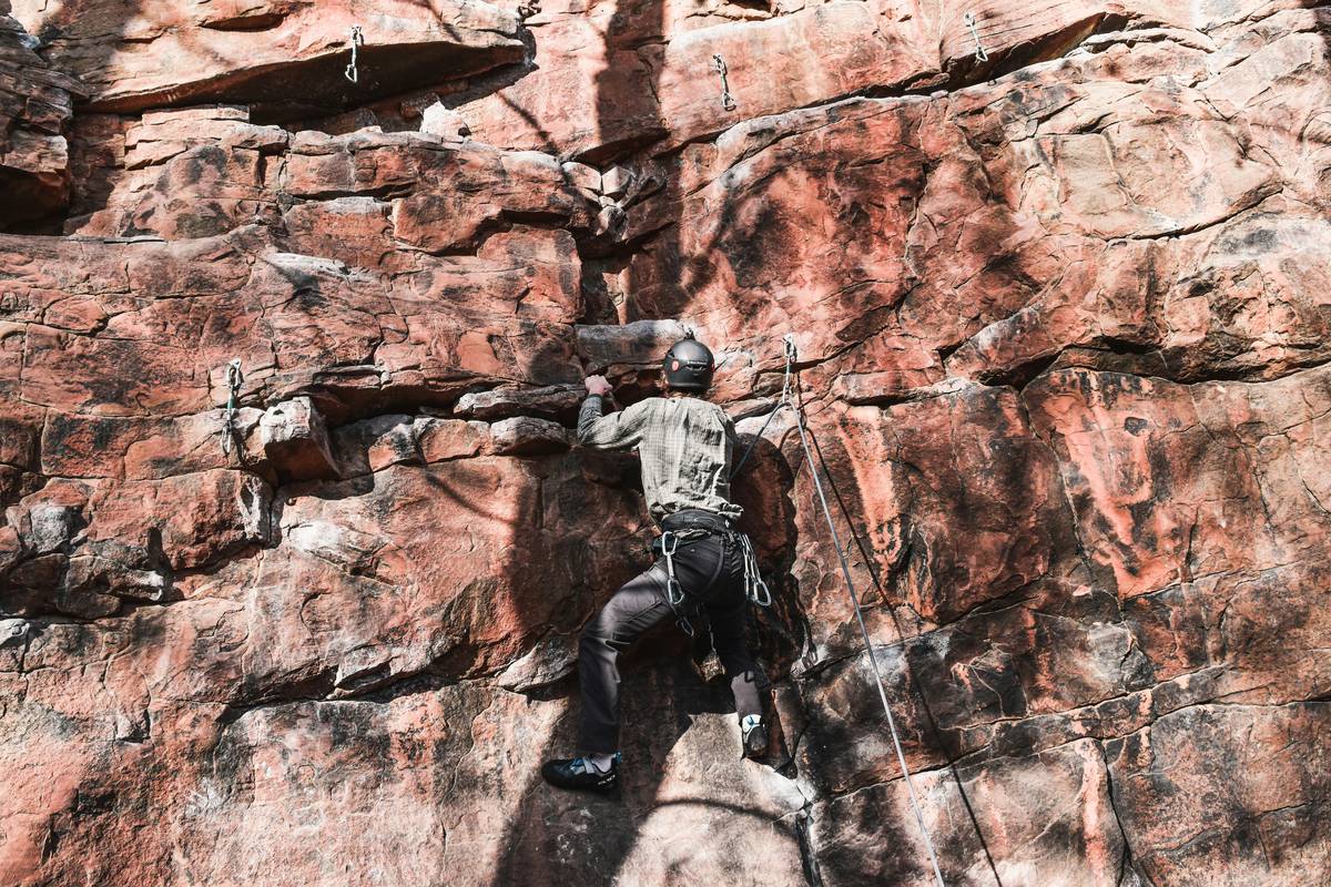 A climber demonstrating proper setup of a belay device attached to harness.