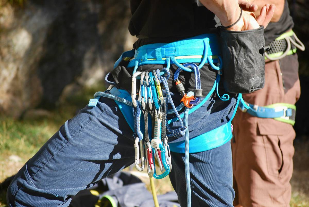 A climber holding a secure belay tool attached to their harness.
