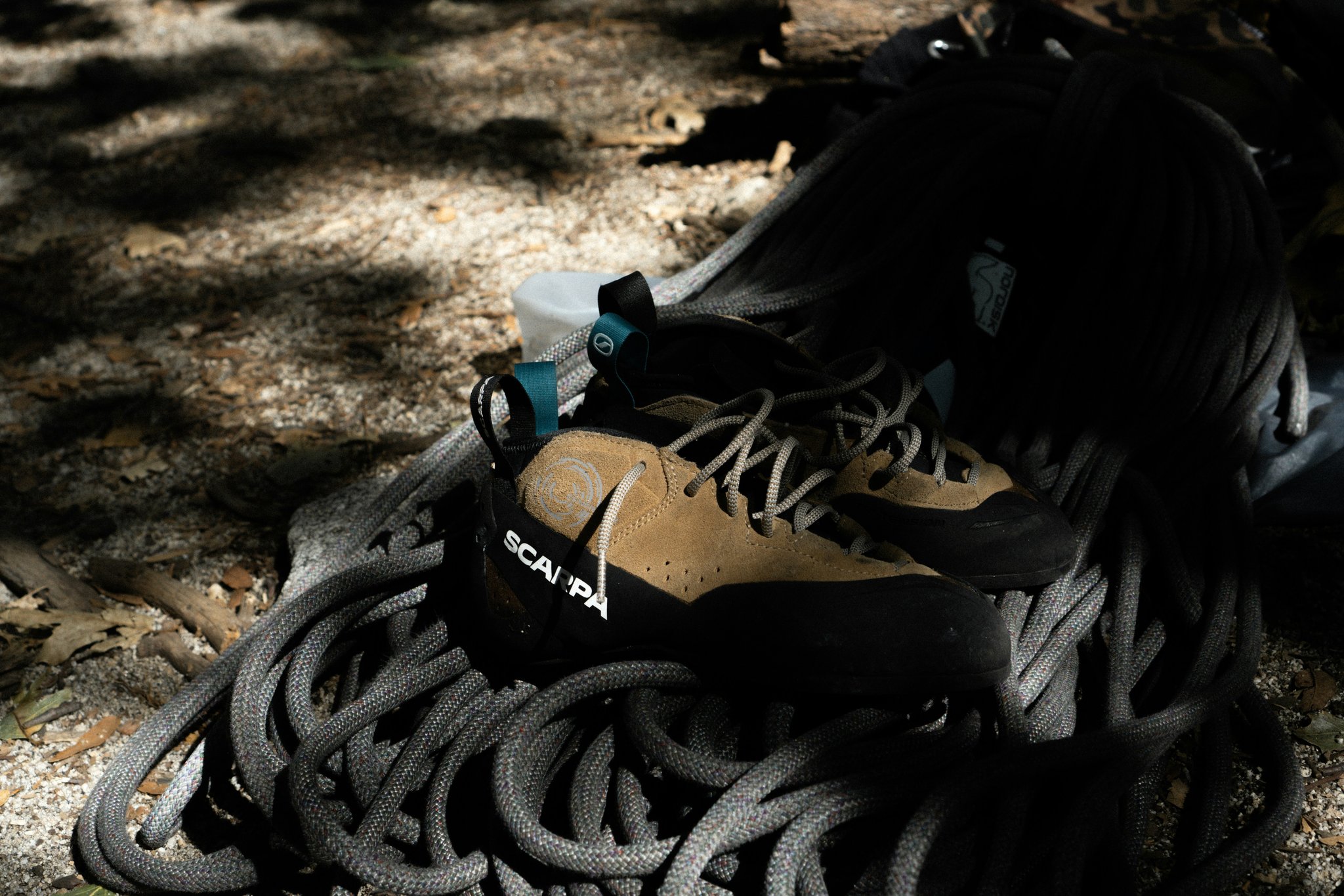 Close-up of a climber's hand holding a modern belay device securely attached to rope.