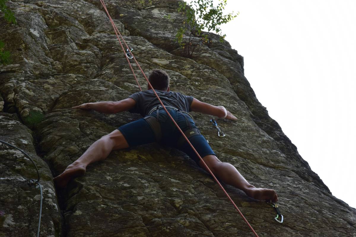Smiling climber holding belay device after successful ascent