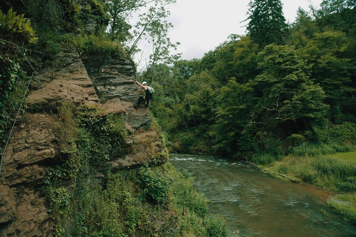 Diagram showing components of a belay rope handling system: belay device, rope path, brake hand position, climber, anchor, and communication signals