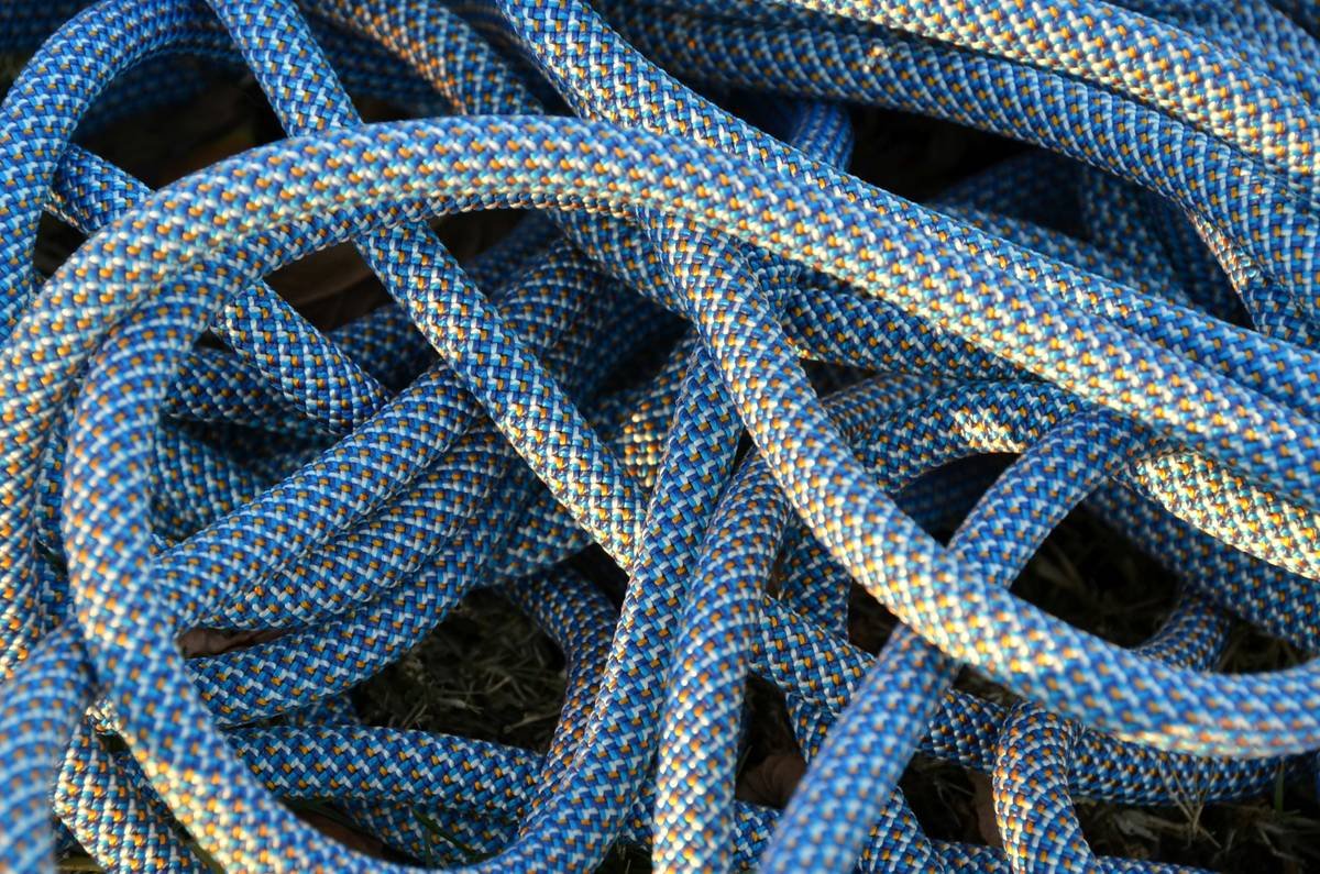 Side-by-side comparison of three common rope management device tools: Petzl Rope Catcher, Edelrid Rope Bag with integrated clip-in points, and Black Diamond GridLock carabiner used with rope stacking technique
