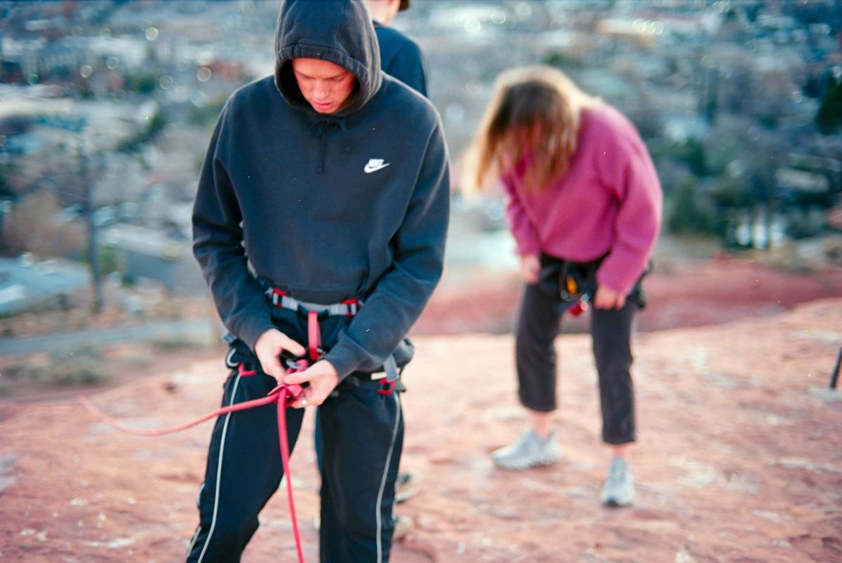 Climber testing auto belay outdoor tips on granite cliff with proper anchor setup