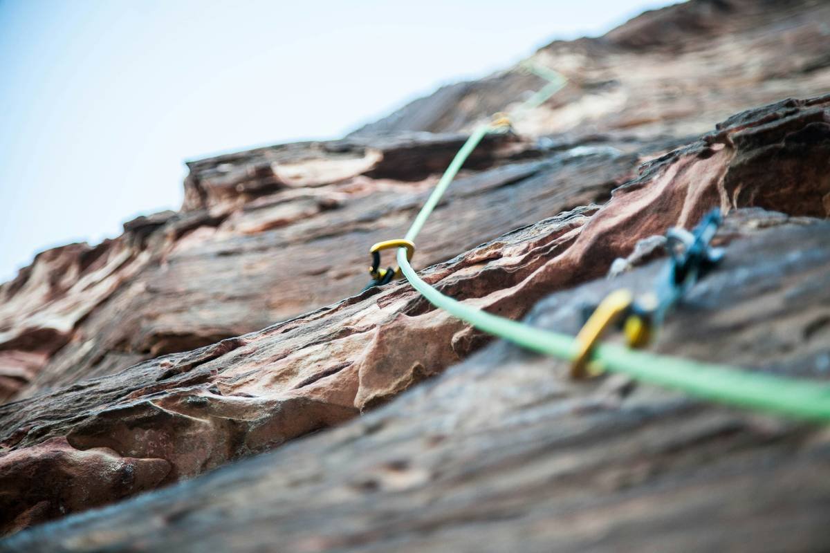 Climber using auto belay outdoor benefits on single-pitch sport route with proper top anchor setup