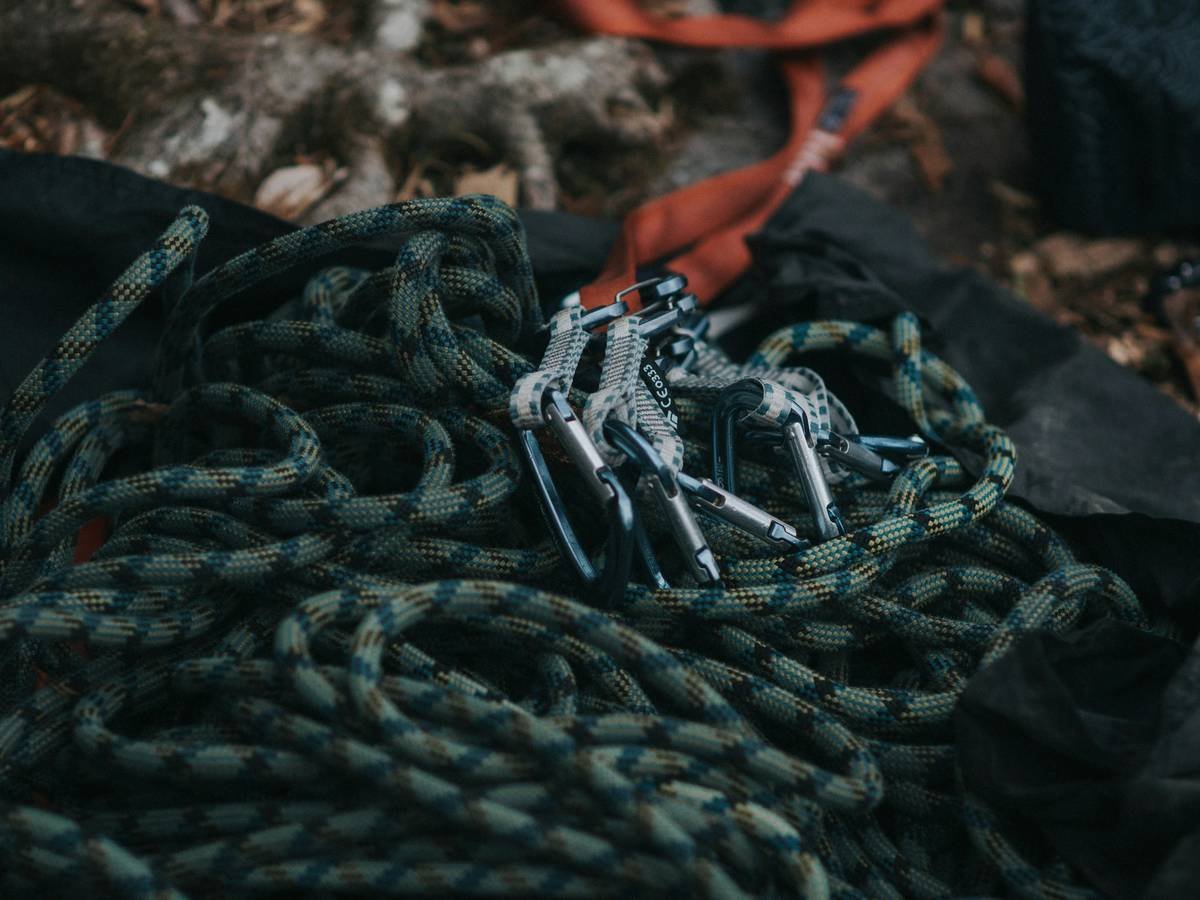 Close-up of auto belay outdoor benefits showing rope feeding through weather-resistant mechanism on dusty cliff edge